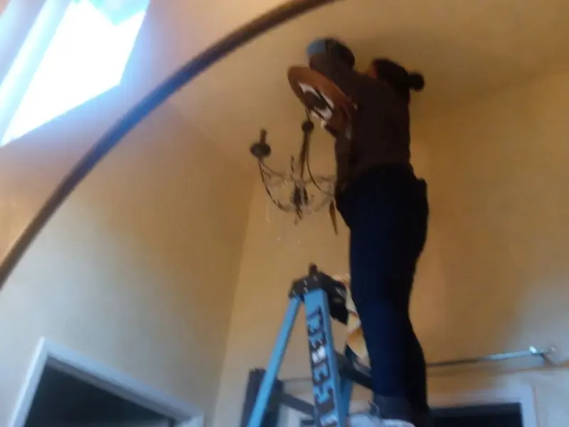 Electrician installing a chandelier in a Roland residence